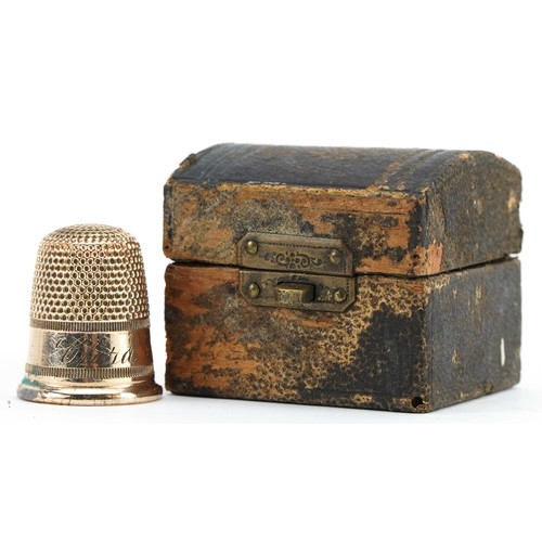 1012A - Yellow metal thimble housed in a tooled leather box in the form of a chest, the thimble 2.1cm high