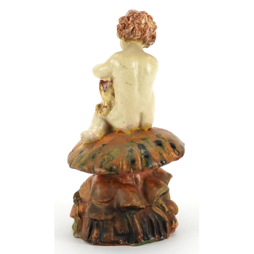 285 - Art Deco pottery figure of a young nude boy hugging a cat seated on a toadstool, indistinctly signed... 