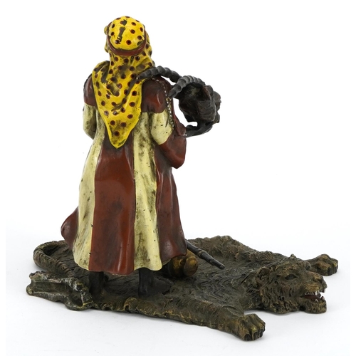 608 - Modern cold painted bronze of an Arab holding an animal skull on a bearskin rug in the style of Fran... 