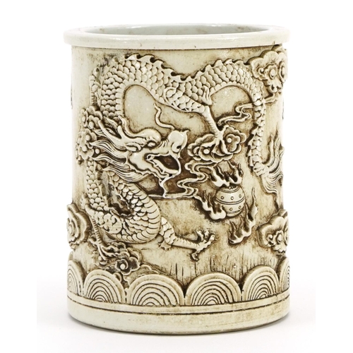 1049 - Chinese blanc de chine porcelain brush pot decorated in relief with a dragon chasing the flaming pea... 