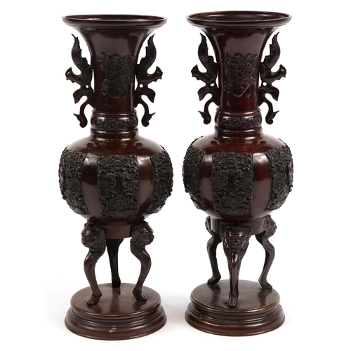 347 - Pair of Japanese patinated bronze three footed vases with twin handles on circular bases, each cast ... 