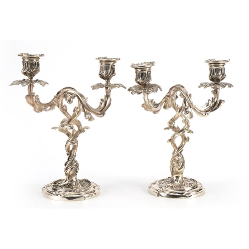 19 - Pair of Rococo style silvered acanthus design two branch candelabras, each 26cm high