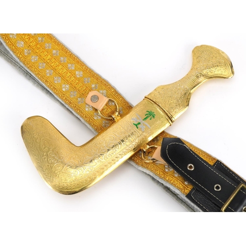 815 - Omani ceremonial gilt metal jambiya dagger on embroidered belt, the dagger 27cm high