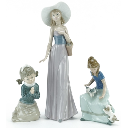 975 - Three Nao porcelain figurines including a girl with puppies, the largest 32.5cm high