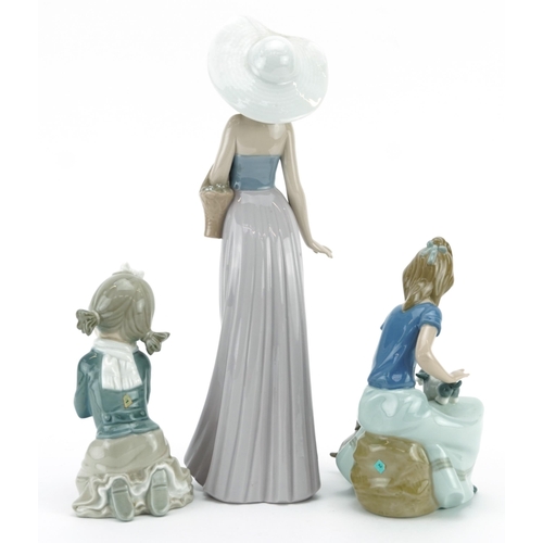 975 - Three Nao porcelain figurines including a girl with puppies, the largest 32.5cm high