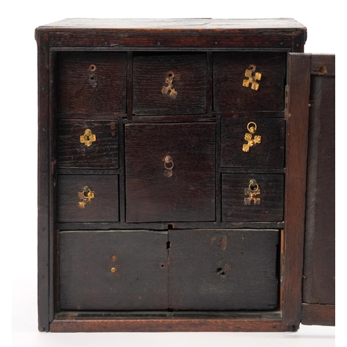 312 - 18th century carved oak spice cupboard with hinged door opening to reveal nine various sized drawers... 