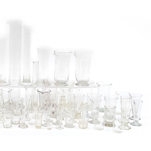 553 - Large collection of antique and later medical interest glass measures, the largest 47cm high