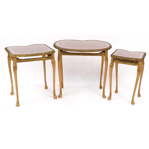 900 - Nest of three kidney shape occasional tables with tooled leather tops and glass inserts, the largest... 