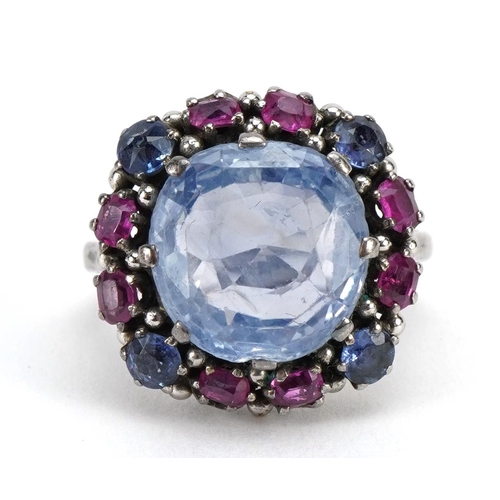 1519 - Silver blue stone and ruby cluster ring, some test as sapphires, the central stone approximately 11.... 