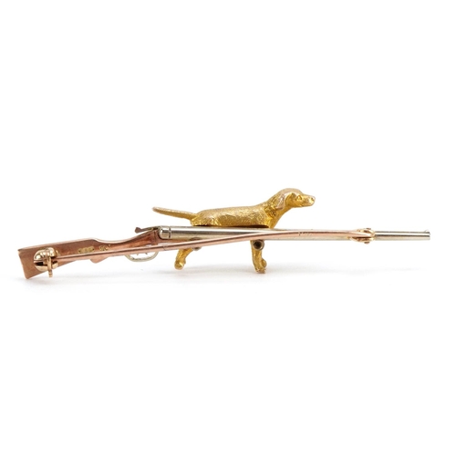 1060 - Hunting interest 9ct three tone gold shotgun and dog bar brooch, 6.4cm wide, 7.1g