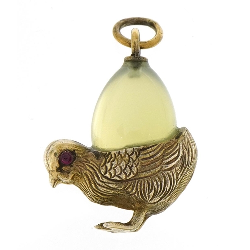 1148 - Silver gilt bird pendant with green stone egg and cabochon ruby eyes, the egg possibly jade, 2.7cm h... 