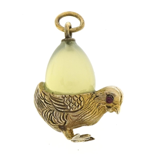 1148 - Silver gilt bird pendant with green stone egg and cabochon ruby eyes, the egg possibly jade, 2.7cm h... 