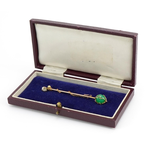 1101 - Unmarked gold green hardstone and pearl stickpin with chain, housed in a tooled leather box, 7.3cm i... 