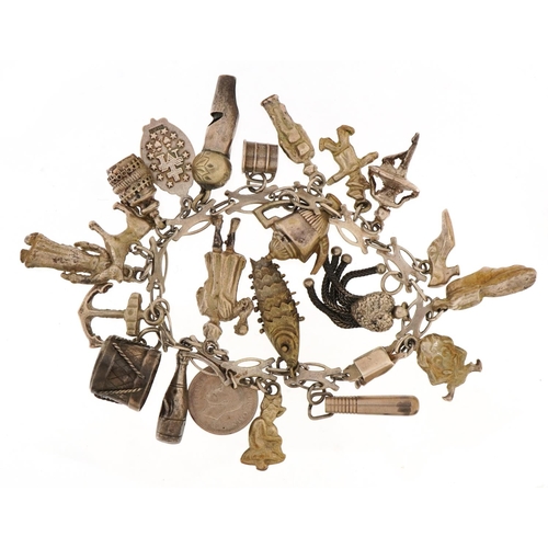 1521 - Unmarked silver charm bracelet with a selection of mostly silver charms including whistle, articulat... 