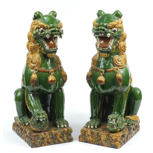 127 - Large pair of Chinese floor standing pottery seated lions having a sancai type glaze, each 59cm high