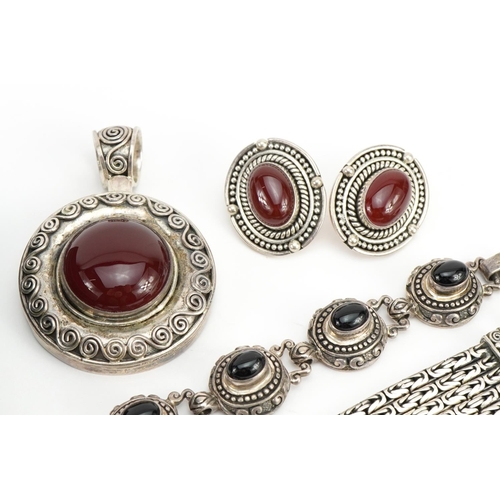 1577 - Middle Eastern silver jewellery comprising two bracelets set with cabochon stones and a pendant with... 