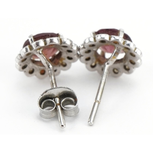 2077 - Pair of unmarked white gold garnet and diamond flower head stud earrings, 1.1cm high, 3.0g