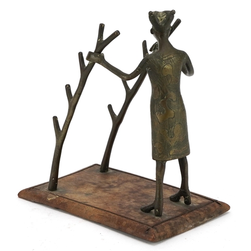 488 - Tribal interest bronze pen-rest on hardwood stand in the form of a tribesman holding two trunks, 16.... 