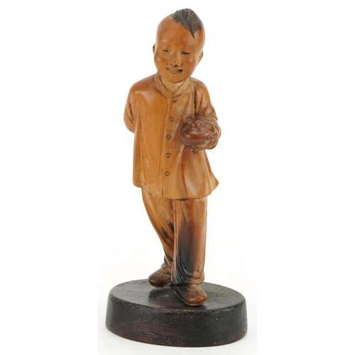 522 - Chinese boxwood carving of a young boy holding a fruit, raised on an oval base, 11cm high