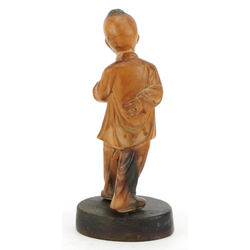 522 - Chinese boxwood carving of a young boy holding a fruit, raised on an oval base, 11cm high