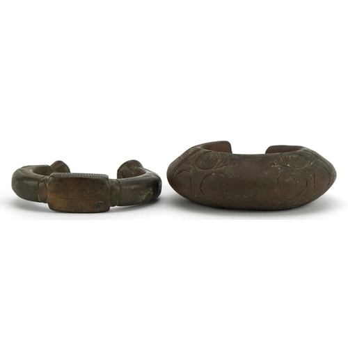 485 - Two Middle Eastern bronze slave bangles with incised decoration, the largest 10cm wide