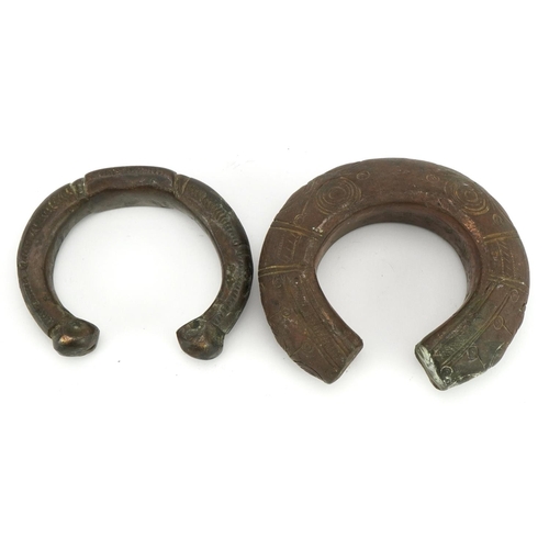 485 - Two Middle Eastern bronze slave bangles with incised decoration, the largest 10cm wide