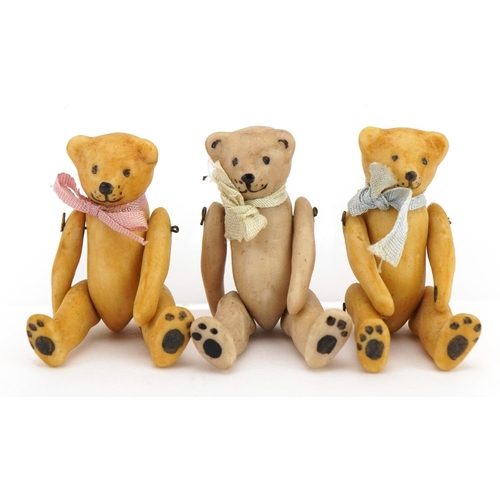 1412 - Three miniature bisque teddy bears with jointed limbs in the manner of Hertwig, each 3.7cm high