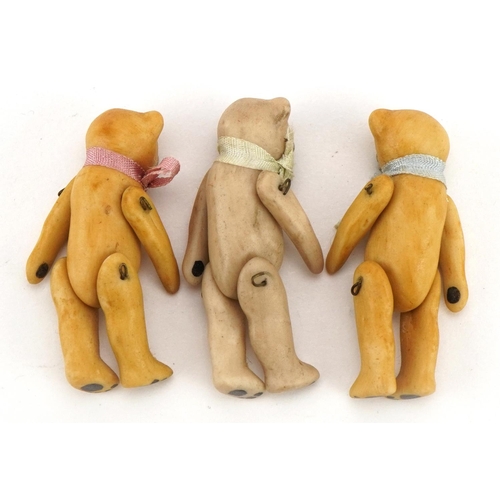 1412 - Three miniature bisque teddy bears with jointed limbs in the manner of Hertwig, each 3.7cm high