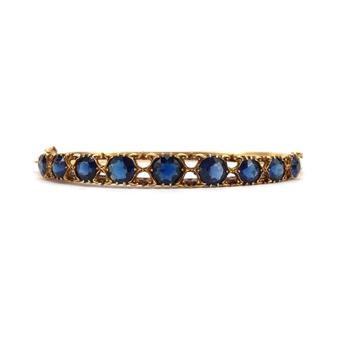 2065 - Victorian 15ct gold hinged bangle set with nine graduated blue stones, 6.5cm wide, 14.5g