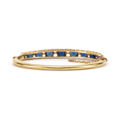 2065 - Victorian 15ct gold hinged bangle set with nine graduated blue stones, 6.5cm wide, 14.5g