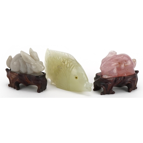 274 - Two Chinese carved jade and rose quartz rabbits with hardwood stands and a carved jade fish, the lar... 