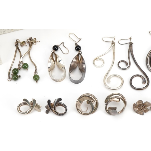 2628 - Nine pairs of silver earrings including flower head studs and one set with green stones, each housed... 