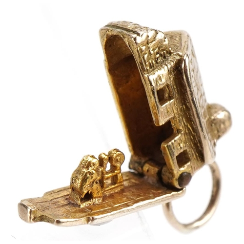 2565 - 9ct gold cottage charm opening to reveal a figure and spinning wheel, 1.7cm wide, 3.1g