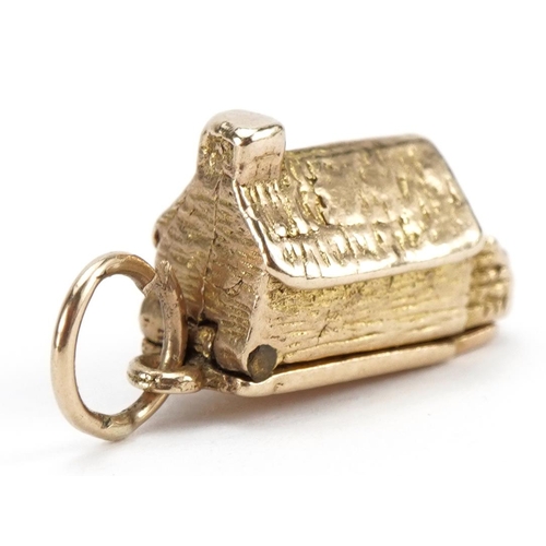 2565 - 9ct gold cottage charm opening to reveal a figure and spinning wheel, 1.7cm wide, 3.1g