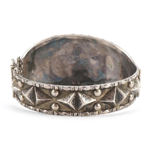 2570 - Antique unmarked silver and amethyst hinged bangle with pierced and embossed decoration, 6.7cm wide