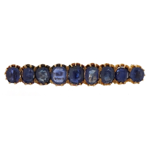 2104 - Unmarked gold sapphire brooch set with nine graduated stones housed in a velvet box, the largest sap... 