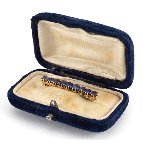 2104 - Unmarked gold sapphire brooch set with nine graduated stones housed in a velvet box, the largest sap... 