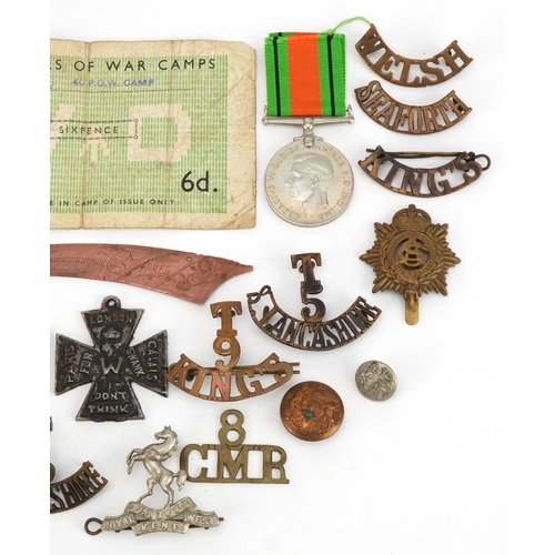 661 - British militaria including shoulder titles, cap badges and World War II Defence medal