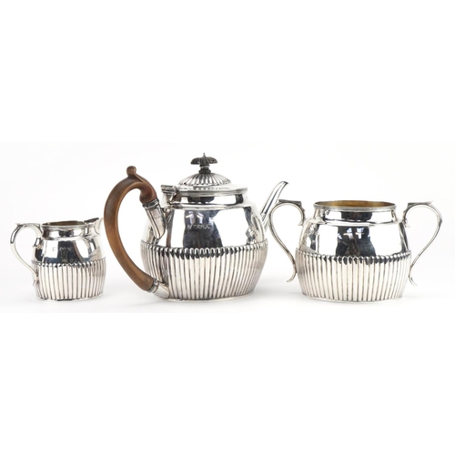 2660 - Lambert & Co, Victorian silver three piece tea service with demi fluted body, the teapot with wooden... 