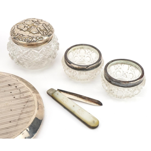 2764 - Silver mounted objects including a mother of pearl folding fruit knife, cut glass salts and a dressi... 