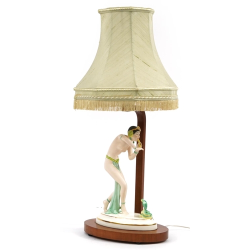 34 - Art Deco walnut table lamp mounted with a Czechoslovakian porcelain figurine of a snake charmer, the... 