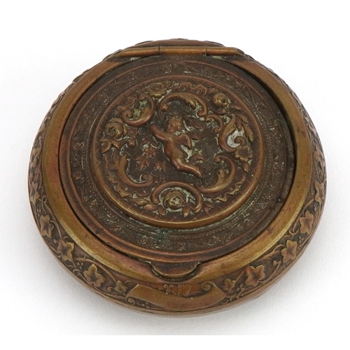 224 - 19th century circular brass snuff box with hinged lid, decorated in relief with Putti, 5cm in diamet... 