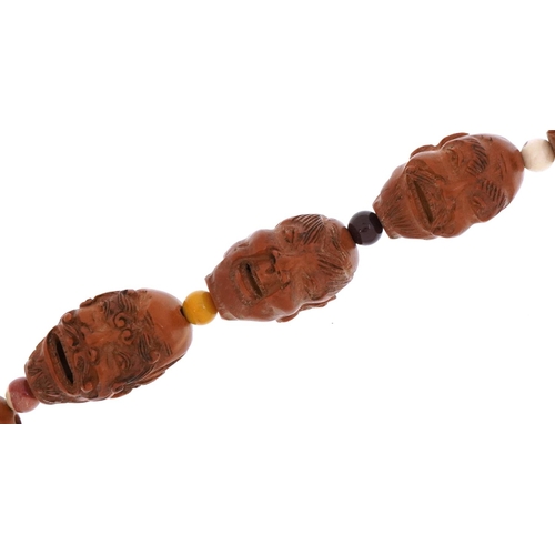 47 - Chinese coquilla nut necklace carved with faces of elders and Buddhas, 67cm in length
