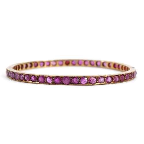 3055 - Unmarked gold ruby hinged bangle, possibly Victorian, tests as 15ct gold, 5.7cm in diameter, 12.0g