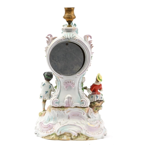 275 - German porcelain floral encrusted mantle clock with candleholder surmounted with three figures havin... 