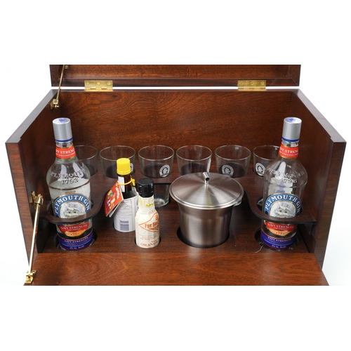 107 - Plymouth Gin mahogany ship's commissioning set with lift up top and drop down front enclosing a bott... 