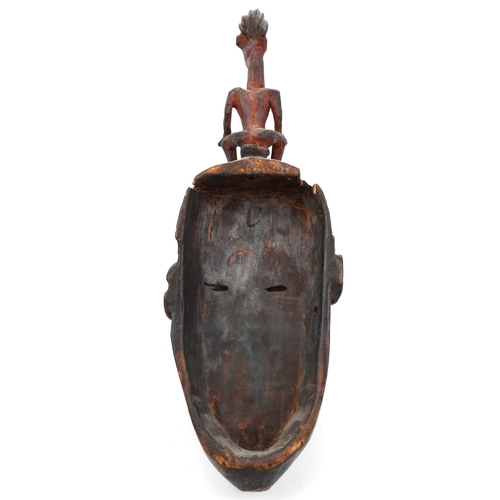 136A - African tribal interest Dogon tribe carved wood face mask surmounted with a nude female, 46cm high