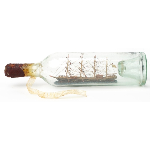 288 - Early 20th century glass ship in a bottle housing a wooden model of a frigate, 34cm high