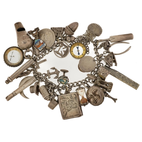 2132 - Large silver charm bracelet with a selection of mostly silver charms including folding pocket knife,... 