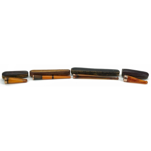 79 - Four late 19th/early 20th century butterscotch amber and amber coloured cigarette holders with 9ct g... 